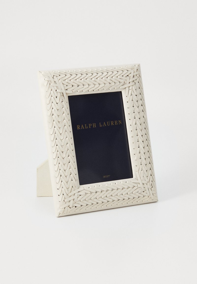Cornice fotografica bianca intrecciata con bordo testurizzato e inserti blu navy con la scritta dorata "RALPH LAUREN". Può essere posizionata in verticale.
