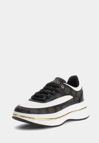 Zapatilla con un patrón de logo negro y dorado, acentos de cuero blanco, parte superior texturizada, suela blanca gruesa con ribete dorado y suela de goma negra.