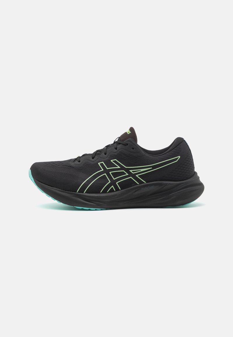 Baskets de sport noires avec tige en mesh, accents verts et semelle rembourrée. Dispose d'un design épuré et d'un système de laçage.