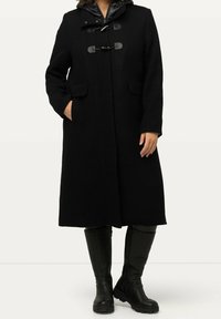 Black wool-blend coat with a detachable padded hood, toggle closures, and side pockets. Worn with knee-high black leather boots.