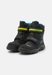 Bottes noires pour enfants avec des accents bleus, en matériau synthétique, deux bandes Velcro, semelle en caoutchouc, col rembourré et détails réfléchissants.