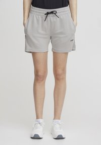 Lys grå treningsshorts med elastisk midjebånd, snor, sidelommer og en liten logo nær kanten. Glatt, pustende stoff.