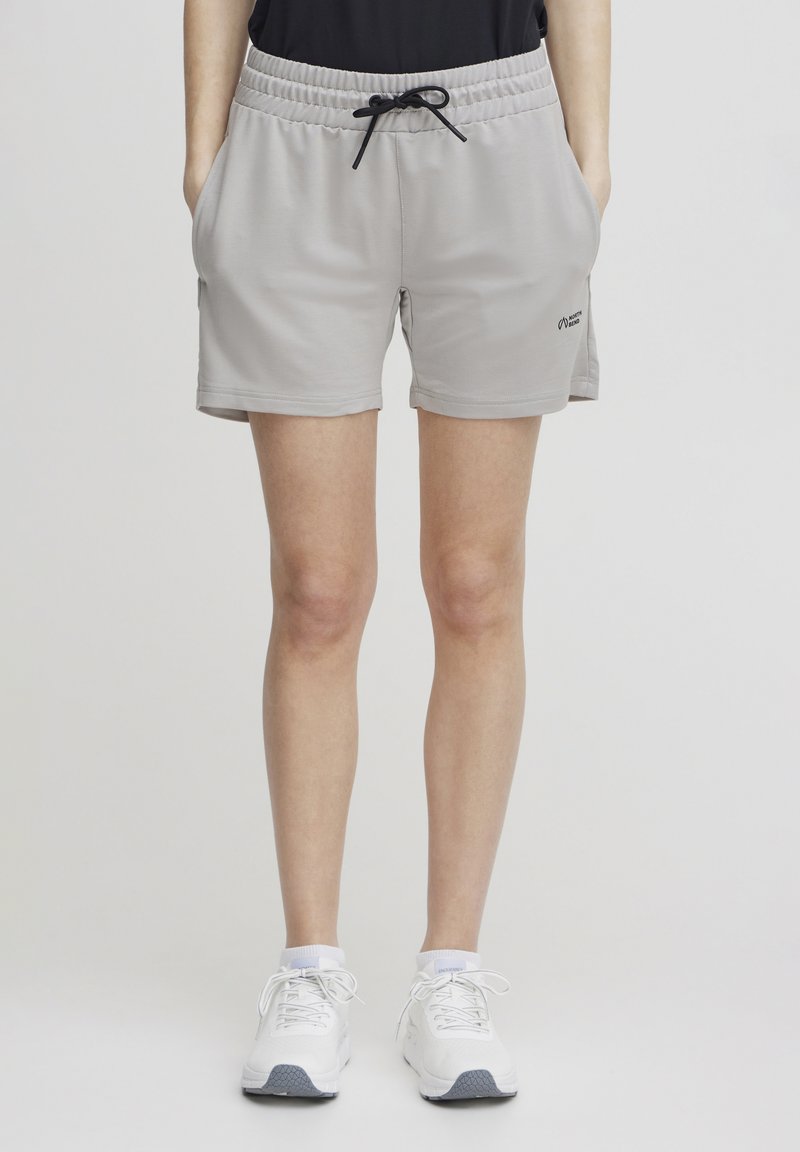 Lys grå treningsshorts med elastisk midjebånd, snor, sidelommer og en liten logo nær kanten. Glatt, pustende stoff.