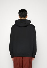 Sweat à capuche noir avec une coupe décontractée, doté d'une poche kangourou et de poignets côtelés. Tissu doux et design minimaliste.