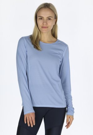 Light blue long-sleeve athletic top with a round neckline, textured fabric, and subtle stitching details, paired with dark leggings.