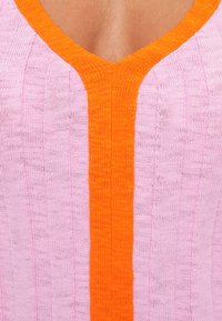 Pletena majica u ružičastoj i narančastoj boji, s V-izrezom, uzdužnim prugastim uzorkom i rebrastom teksturom duž šavova.