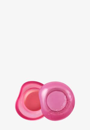 Boîte ronde rose de baume à lèvres avec le couvercle enlevé, montrant le produit lisse à l'intérieur, sur fond blanc.