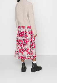 Beige ribbed sweater, floral midi skirt in pink hues with green accents, and black ankle boots. Fitted top with flared skirt silhouette.