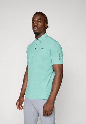 Mint green polo shirt with short sleeves, featuring a pointed collar, three black buttons, and "Calvin Klein" logo on the sleeve.
