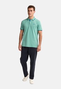 Mäta zelená polokošeľa s dvomi gombíkmi a námorníckymi akcentmi. V kombinácii s tmavými cargo nohavicami a bielymi teniskami. Voľný strih.