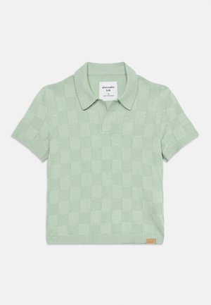 Polo de manga corta de punto en verde claro con un patrón de cuadros, puños acanalados, cuello y una pequeña etiqueta de la marca en el dobladillo.