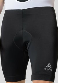 Shorts de cyclisme noirs en matériau extensible, dotés d'un insert rembourré et d'un logo sur le bas de la jambe. Design ajusté, au-dessus du genou.