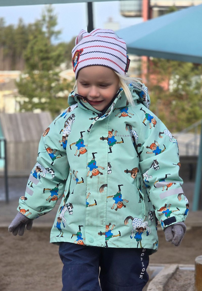 Vattentät mintgrön jacka med lekfulla karaktärstryck. Har huva och reflexdetaljer. Matchad med mörka byxor och handskar.