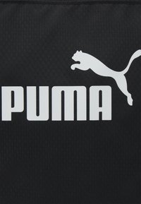 Logo Puma blanc avec un puma bondissant au-dessus du texte "PUMA" en majuscules blanches et en gras sur un fond noir texturé.