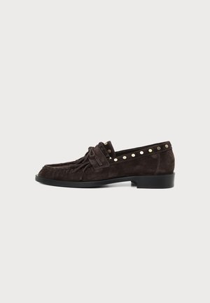 Mocasín de ante marrón oscuro con flecos y detalles de tachuelas a lo largo del borde superior, tacón plano y puntera redondeada, mostrado de lado.