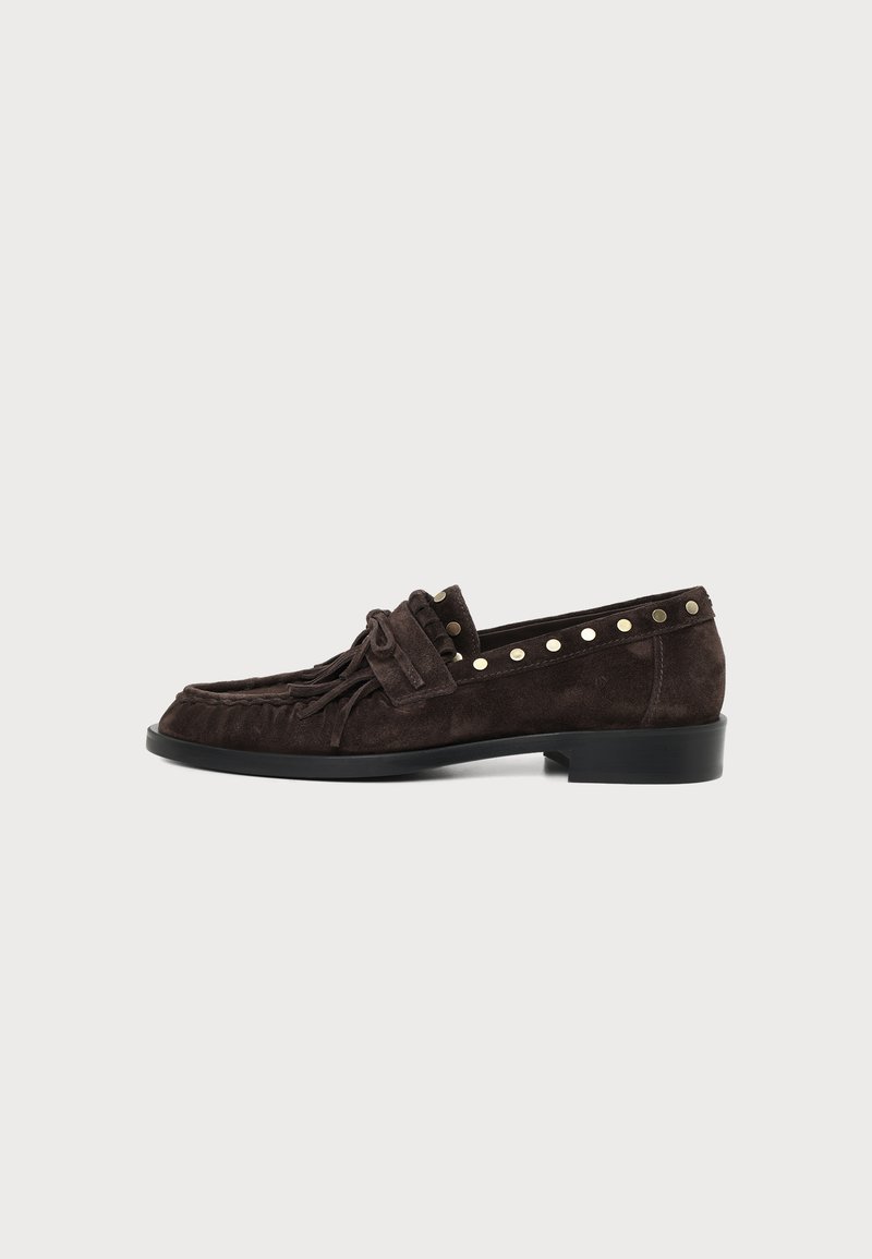 Mocassin en daim marron foncé avec franges et détails cloutés sur le bord supérieur, talon plat et bout arrondi, vu de côté.