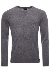 Pull gris en maille avec manches longues, encolure ronde et texture côtelée. Présente une petite étiquette logo en bas à gauche de l'ourlet.