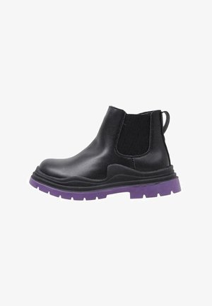 Bota Chelsea de cuero negro con panel lateral elástico y suela gruesa de caucho púrpura, vista desde el lado exterior.