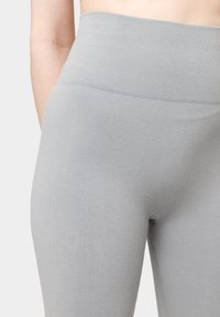 Leggings grigi chiaro a coste con vita alta e texture liscia, caratterizzati da una silhouette aderente senza cuciture o motivi visibili.