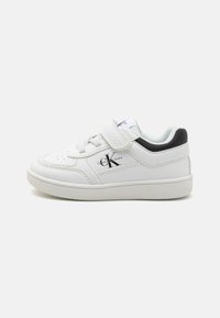 Baskets blanches en cuir avec un design texturé. Présentent une sangle Velcro, des lacets et une accent noir au niveau du talon. Logo Calvin Klein visible.
