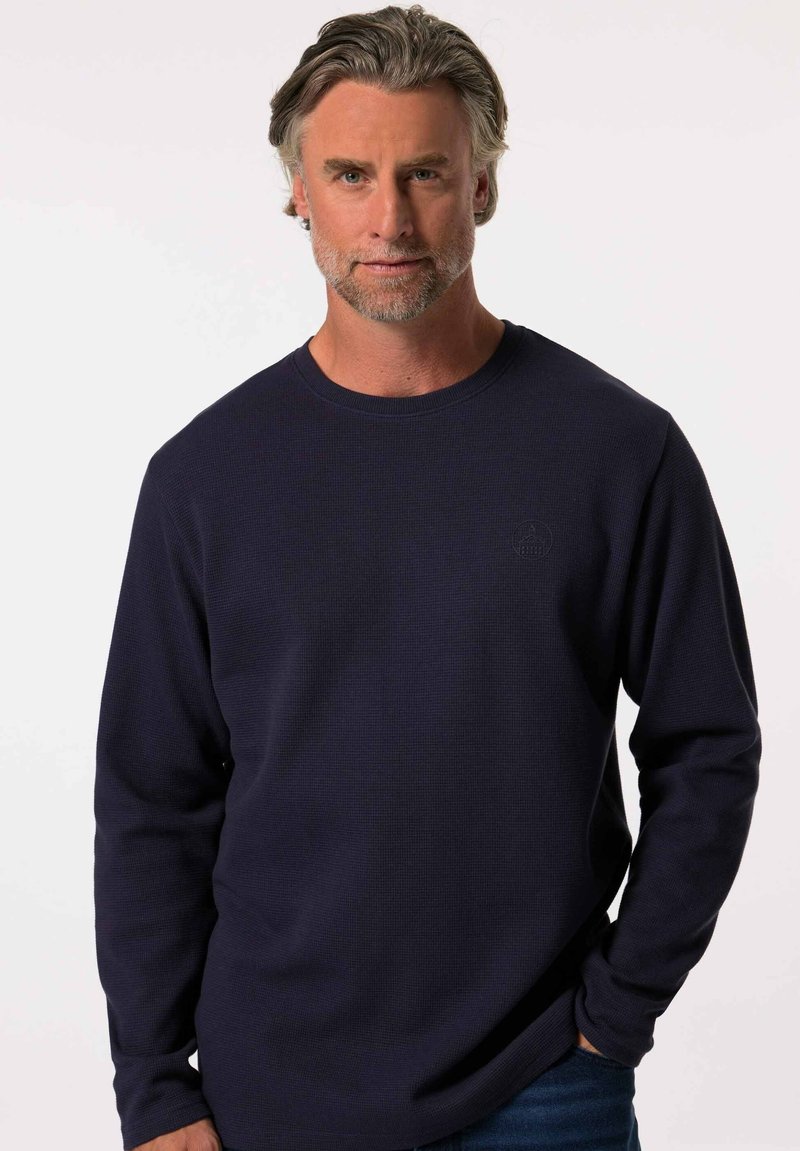 Mörkblå långärmad tröja med rund halsringning i en strukturerad tyg, med en diskret logotypdetalj på bröstet och en avslappnad passform.