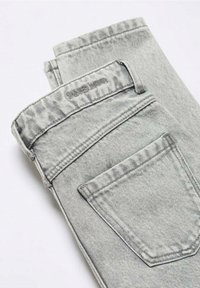 Ljusgrå vikta denimjeans som visar bakfickan, bältesöglor och midjeband med subtil märkessöm.