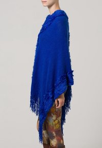 Poncho blu brillante con bordo frastagliato testurizzato, realizzato in tessuto morbido. Presenta un orlo asimmetrico e un design accogliente con colletto a scialle.