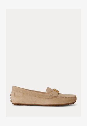 Beige suède loafer met gouden gespdetail, rubberen nopzool en gestikte details langs de zijkanten en teen, zijaanzicht.