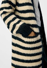 Strickcardigan mit auffälligen schwarzen und cremefarbenen horizontalen Streifen, mit gerippten Bündchen und Taschen, der ein strukturiertes, gemütliches Design präsentiert.