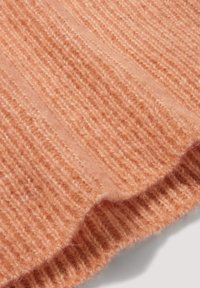 Weicher, flauschiger Strickstoff in Pfirsichfarbe mit gerippten vertikalen Streifen und geschwungenem Saum.
