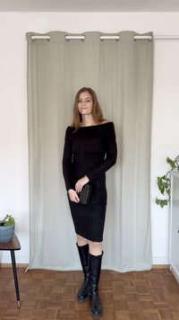 Černé žebrované šaty s odhalenými rameny a dlouhými rukávy, délka nad kolena, doplněné černými kozačkami po kolena a malou černou kabelkou.