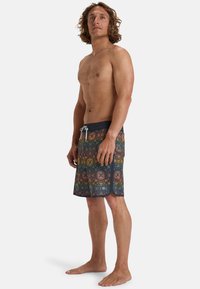 Shorts de bain avec un motif géométrique multicolore, une taille à cordon de serrage et un bord inférieur en noir uni.