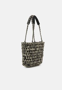 Woven tote bag in black and cream with a textured pattern. Features chained straps and black fabric accents for enhanced grip.