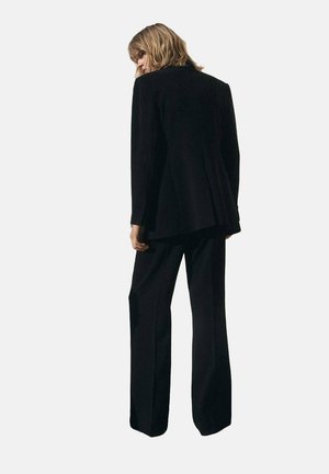 Black tailored suit with a long blazer and wide-leg pants. Smooth texture; no visible patterns or hardware. Back view shown.