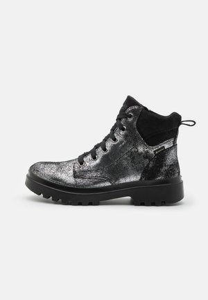 Bottine chelsea noire et argentée avec paillettes. Comprend un dessus texturé, un bout rond et une semelle en caoutchouc avec un motif de semelle. Fermeture à lacets avec une languette.