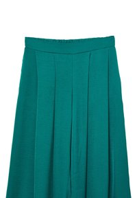 Pantalons larges teal avec plis, présentant une taille plate et un tissu texturé. Le design est fluide et décontracté, adapté à diverses occasions.