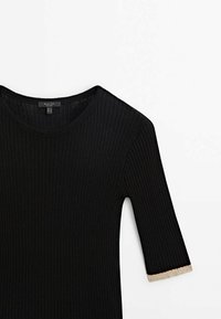 Top nero a coste con scollatura ampia e maniche corte. Le maniche presentano un bordo beige per creare un contrasto. Texture liscia e design aderente.