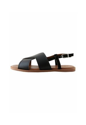 Black leather sandal with crossover strap design, open toe, and ankle strap. Flat, brown rubber sole offers stability and comfort.
