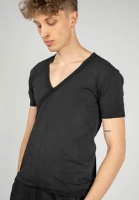 Sort bomulds T-shirt med V-hals og diagonalt sømdesign samt korte ærmer, der har en glat tekstur og en enkel snit.