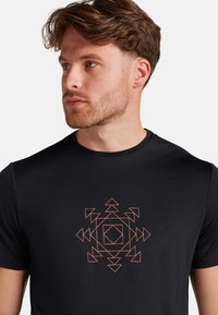 Black t-shirt featuring a geometric design in orange and white. Short sleeves, round neck, smooth texture, with a central patterned graphic.