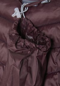 Burgundy pufferjacka i tyg med en samlad huva. Har en dragsnörning och en quiltad struktur. Slät, glänsande yta.