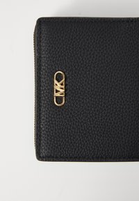 Black textured leather wallet featuring gold-toned hardware with a logo design. Zipper closure and neat stitching detail on edges.