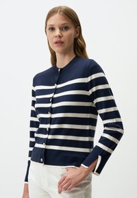 Cardigan a righe blu navy e bianche realizzato in materiale morbido, caratterizzato da un colletto rotondo, chiusura con bottoni e dettagli delle maniche aperte.