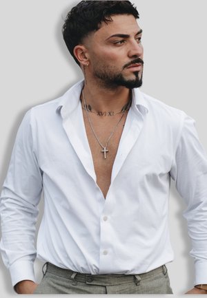 White button-up shirt with a deep V-neck, featuring subtle texture and long sleeves. Worn with gray trousers and layered silver necklaces.
