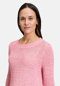 Maglione rosa lavorato a maglia con scollatura rotonda e un motivo testurizzato, caratterizzato da maniche lunghe e una vestibilità comoda.