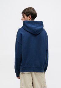 Granatowy sweatshirt z kapturem o luźnym kroju, z ribbowanym dołem i mankietami, miękką teksturą oraz dużym kapturem z tyłu.
