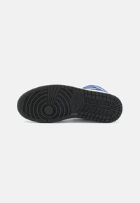 Crna guma potplat s kružnim uzorcima i žljebovima, s izbočenim Nike logotipom. Okvir pokazuje plave i bijele naglaske.