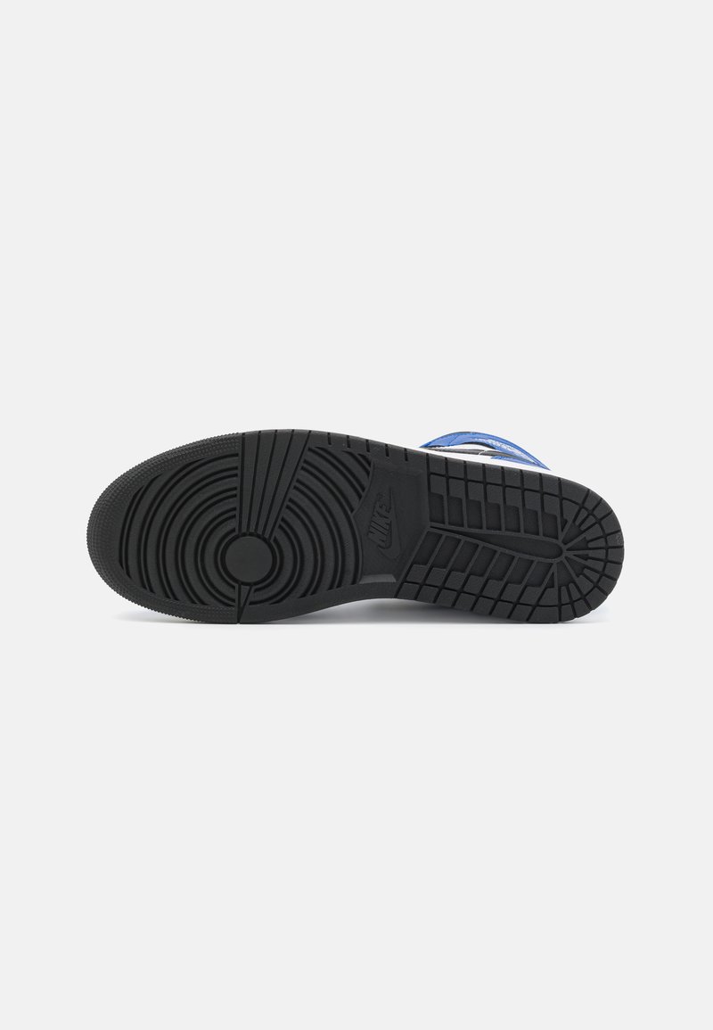 Schwarze Gummisohle mit kreisförmigen Profilmustern und Rillen, mit einem erhabenen Nike-Logo. Der Rahmen zeigt blaue und weiße Akzente.