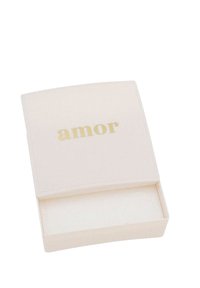 Krämfärgad rektangulär låda med rundade kanter, med ordet "amor" i gyllene bokstäver på locket och en mjuk inredning.