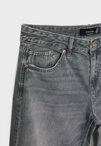 Jeans in denim grigio con una finitura sbiadita, dotati di accessori in rame, design a cinque tasche e un'etichetta che indica la taglia 38.